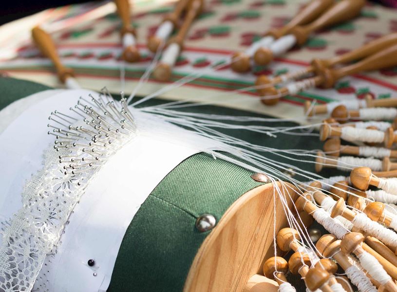 Bobbin lace making with pillow, pins and wooden bobbins in Bruges, Belgium