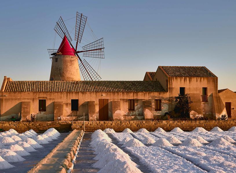 Windmill and salt piles at Salina della Laguna in Marsala, Sicily