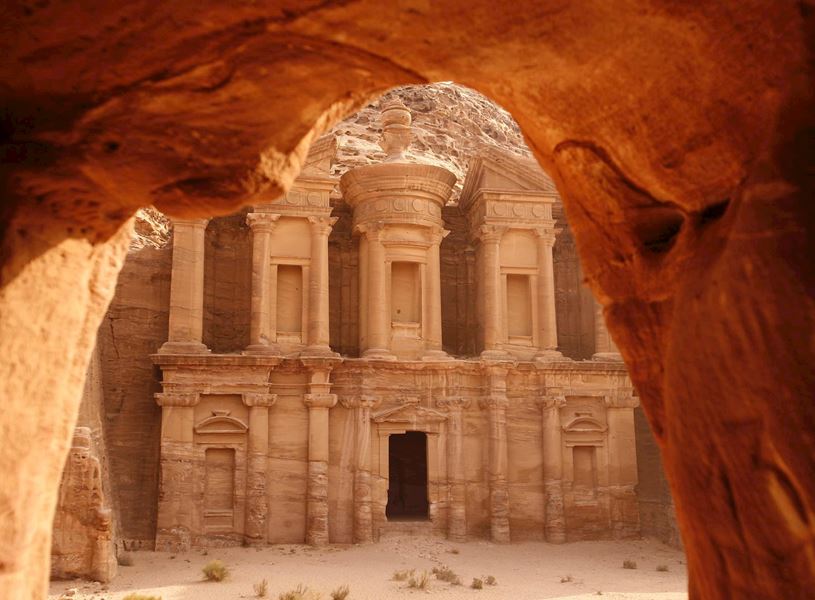 See tombs and temples carved into pink sandstone cliffs, Petra