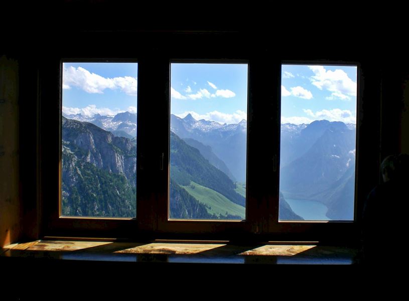 Mountain and lake view through large windows with clear sky and clouds
