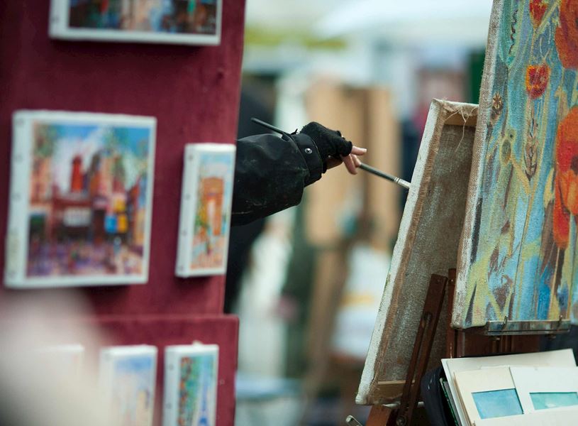 Outdoor artist painting outdoors with displayed canvases 