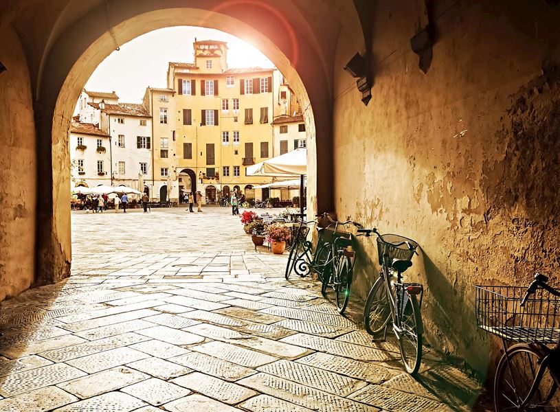 Archway view of Piazza dell’Anfiteatro with bikes leaning on wall in Lucca