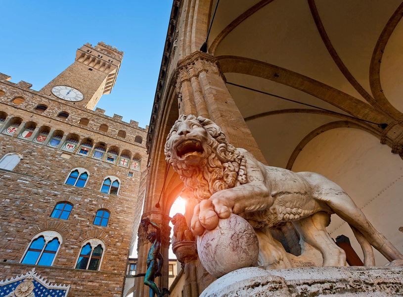 Marble lion statue at Loggia dei Lanzi with Palazzo Vecchio tower