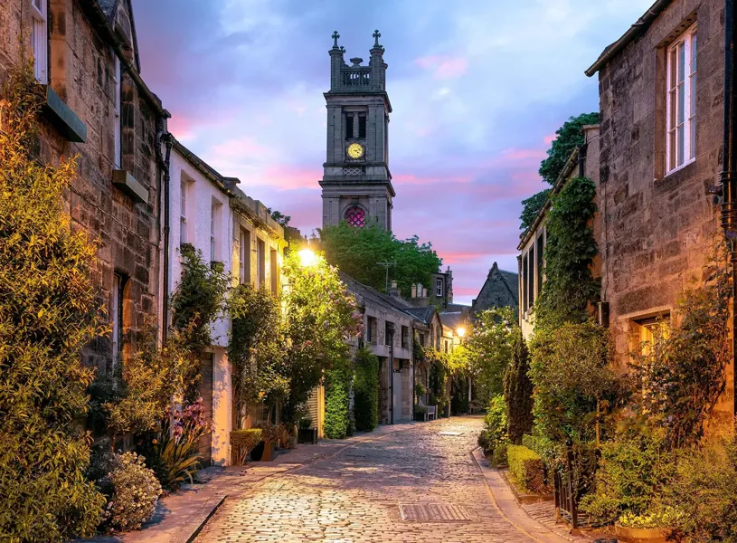 Cobblestone street with historic tower at sunset in Edinburgh, Scotland