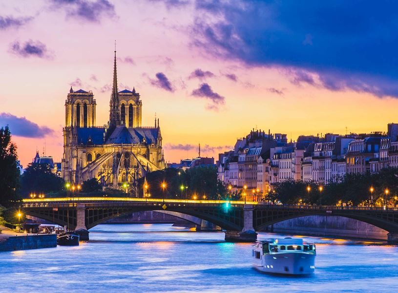 Twilight view of Notre-Dame Cathedral with Seine River and lit bridge 
