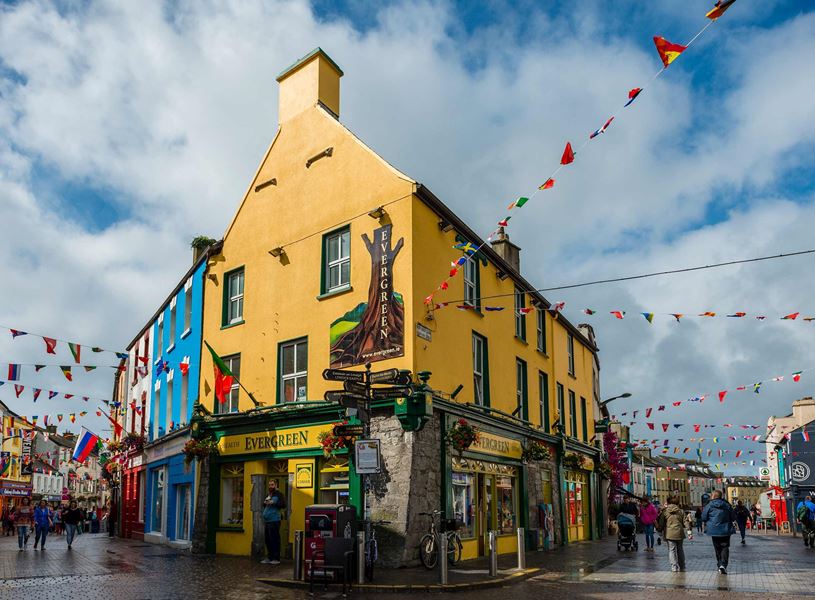 Colourful Galway street with bunting and people walking past shops