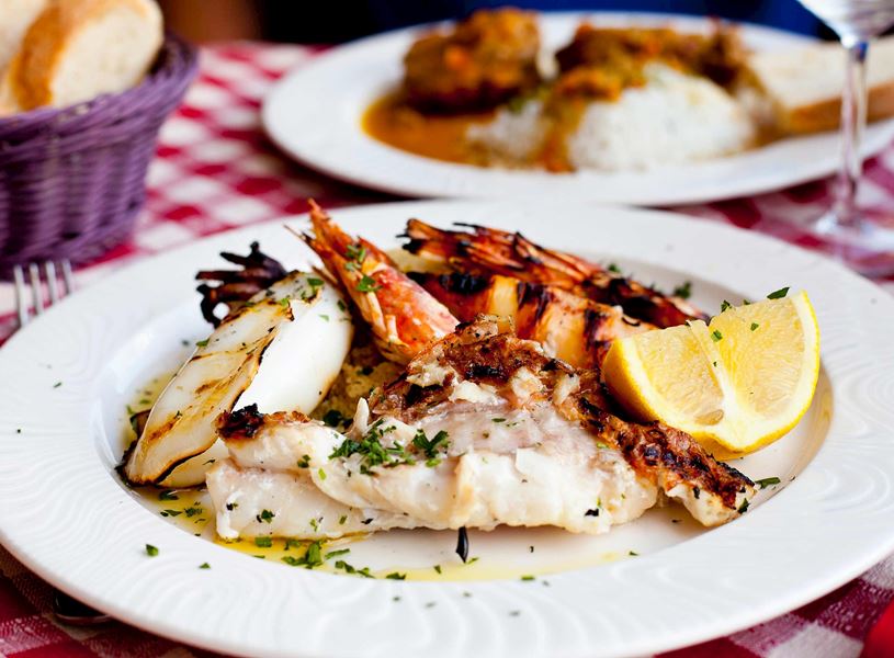 Plate of grilled seafood with lemon wedge on a checkered tablecloth