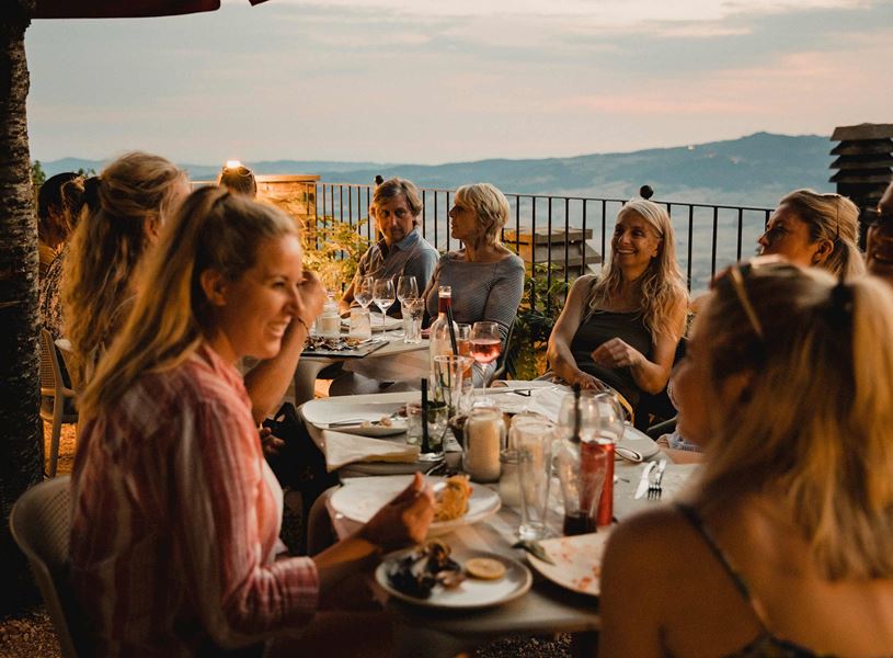 Outdoor dining table with wine glasses and plates overlooking scenic hills