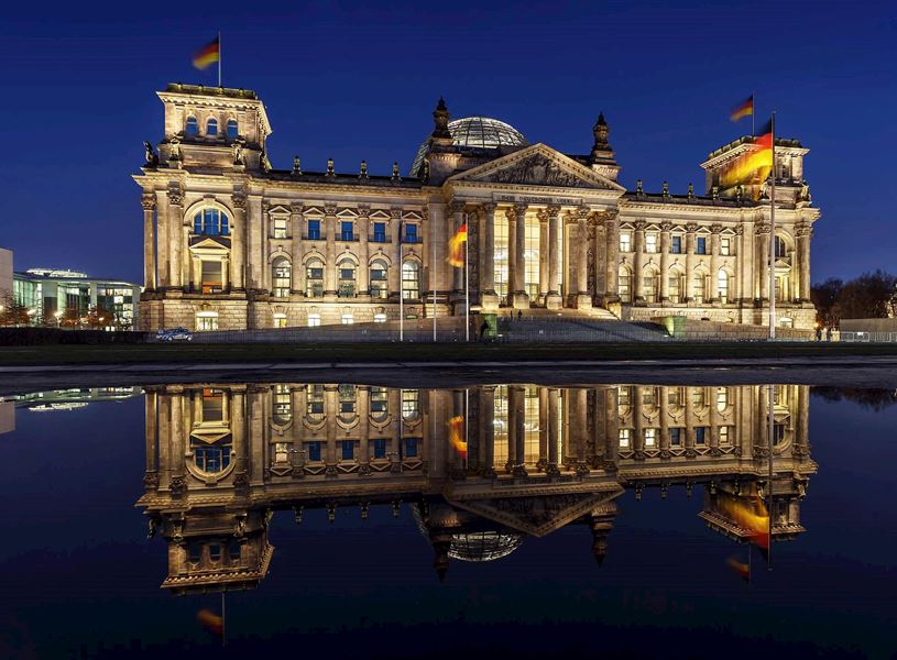 The Reichstag illuminated at night with reflection in water in Berlin, Germany