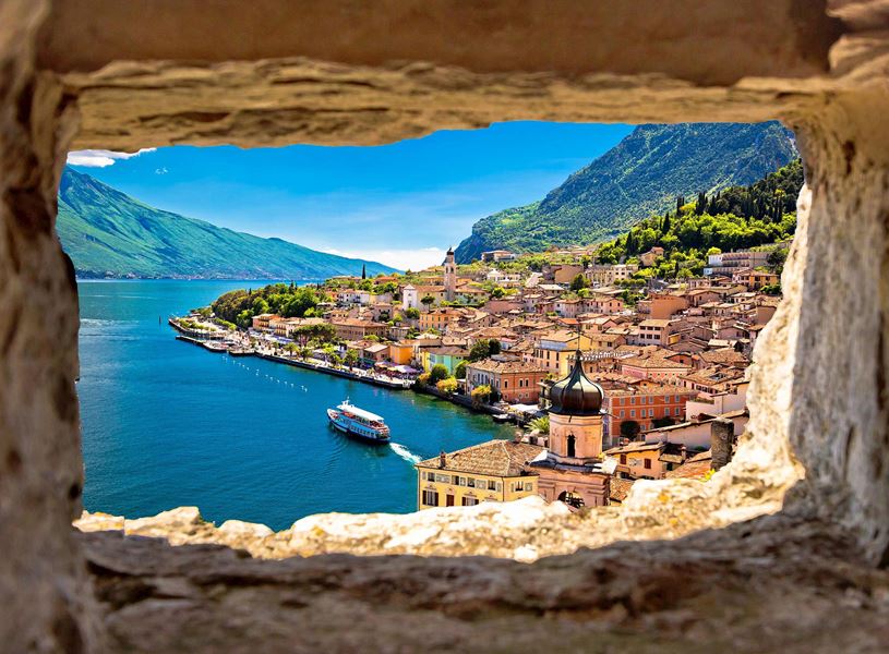 Scenic view of Lake Garda and colourful town framed by stone window