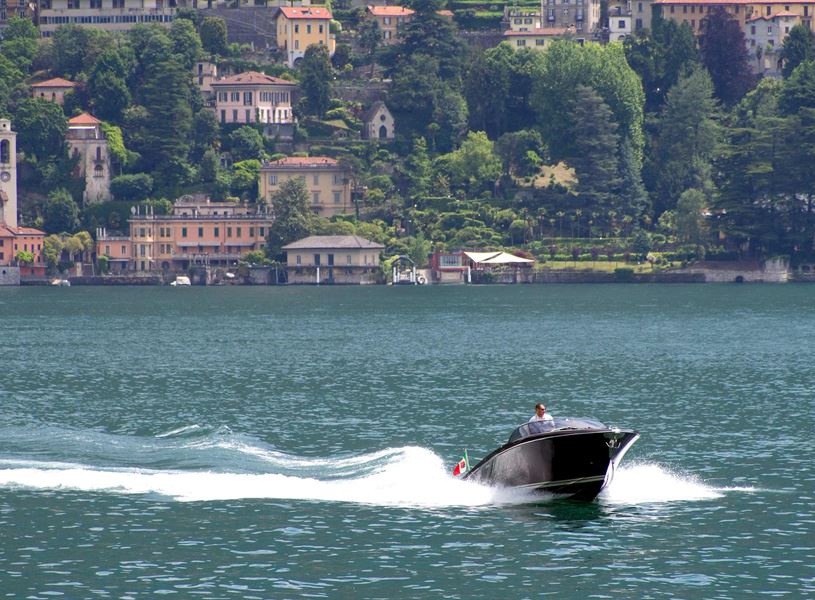 Speedboat cruising on Lake Como with villas in background