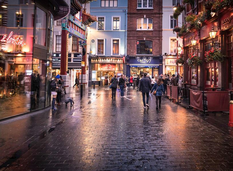 Soho street with shop, restaurants, pub and pedestrians in London, England