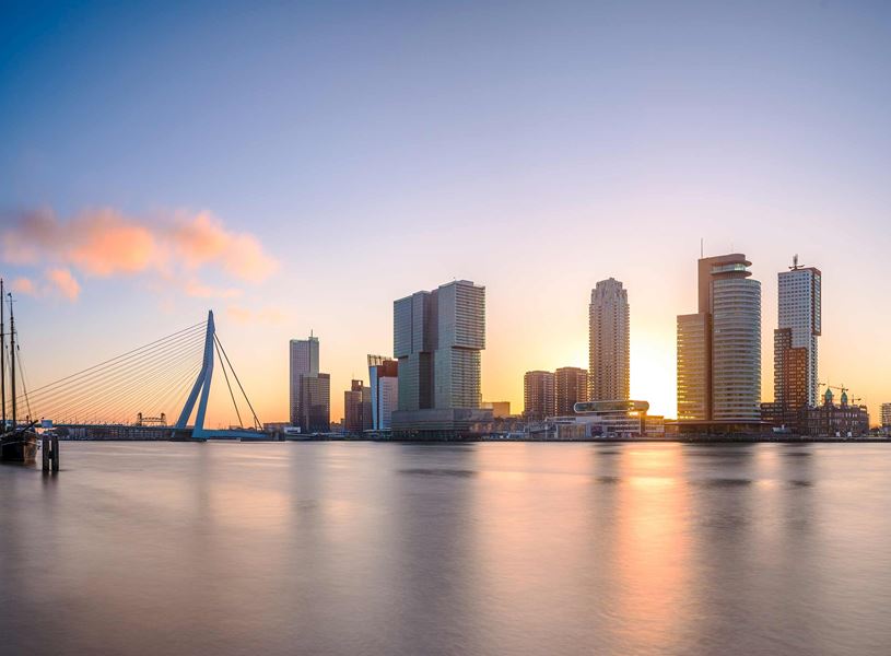 Rotterdam skyline with Erasmus Bridge at sunset over calm water