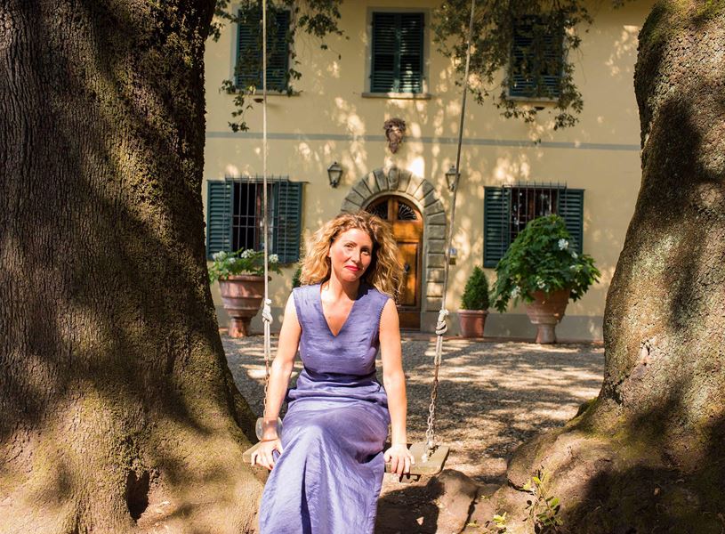 Person sitting on a wooden swing between two large trees in villa garden