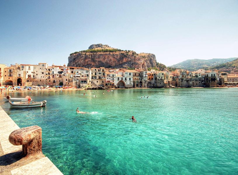 Cefalù coastline with turquoise waters, historic buildings and rocky hill backdrop