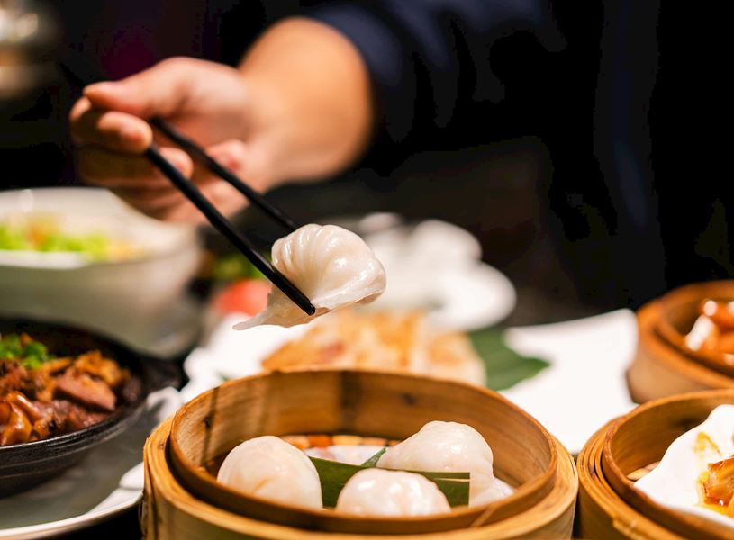 Hand picking up steamed dumpling with chopsticks at Chengdu cooking class