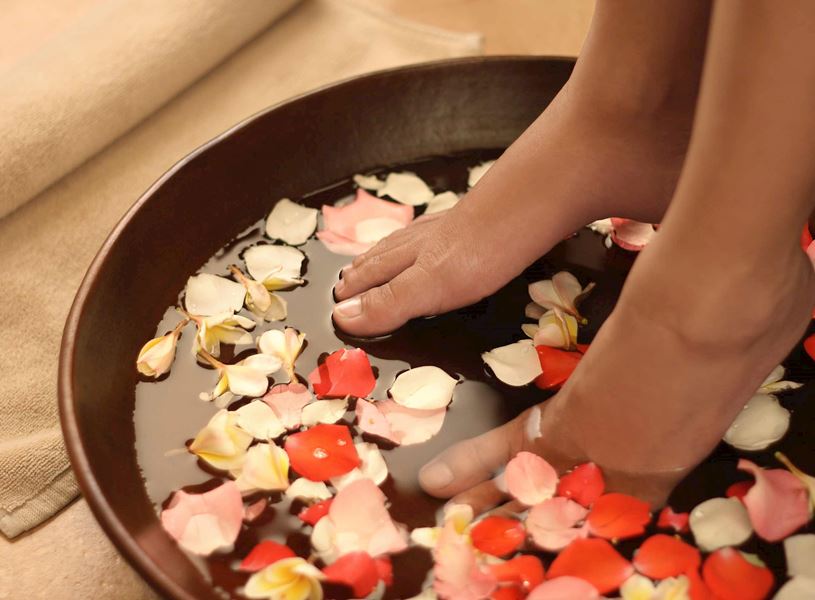 Person’s feet immersed in petal-filled water bowl, China