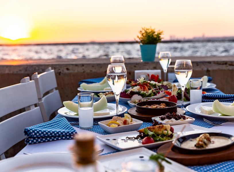 Seaside dinner table with Mediterranean dishes at sunset