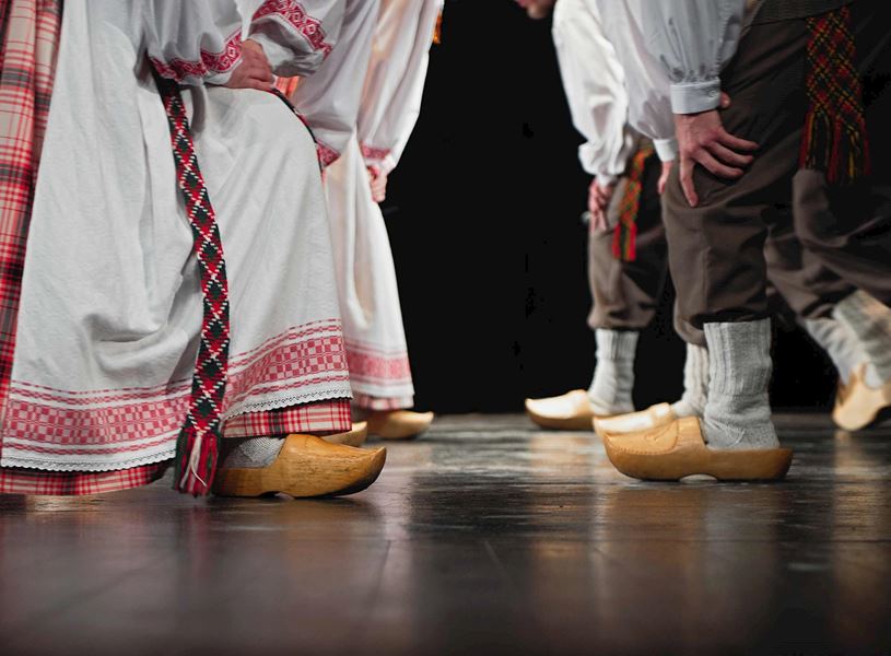 Close-up of traditional Lithuanian folk dancers wearing embroidered costumes and wooden clogs