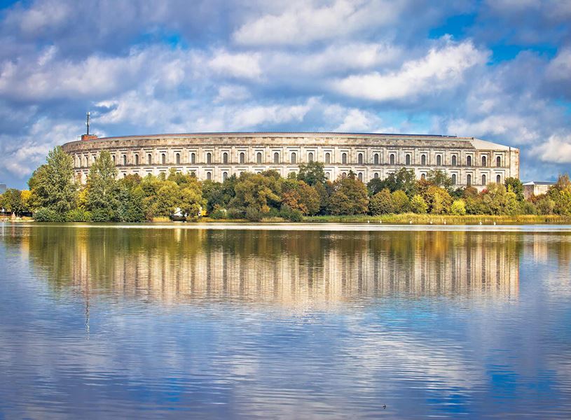 Reich Congress Hall reflected in lake with trees in Nuremberg