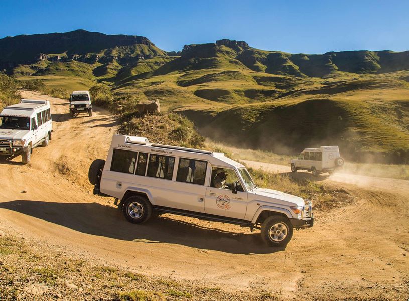 Four safari vehicles on dusty road, Sani Pass, South Africa
