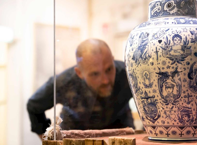 Delft blue ceramic vase with figurative patterns displayed inside pottery factory showroom