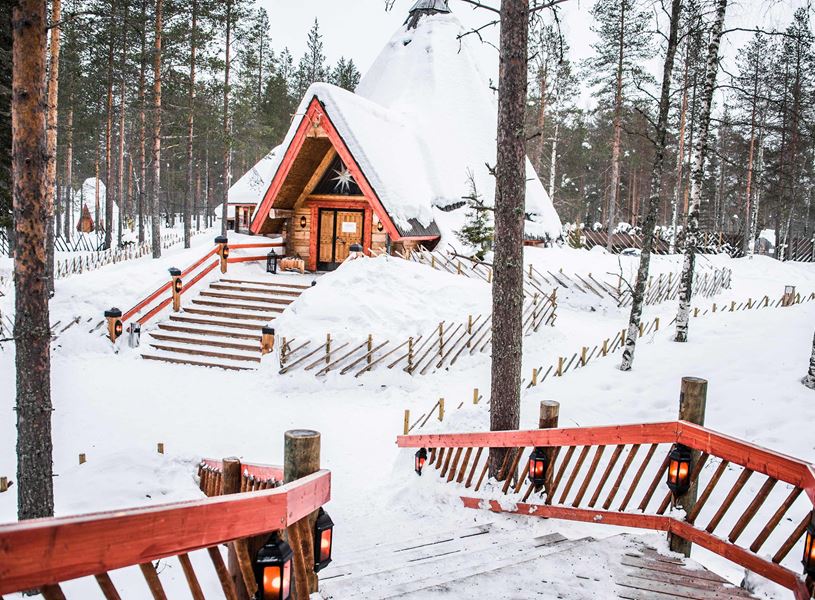 Snow covered cabin with lantern lit stars in Santa Claus Village, Rovaniemi
