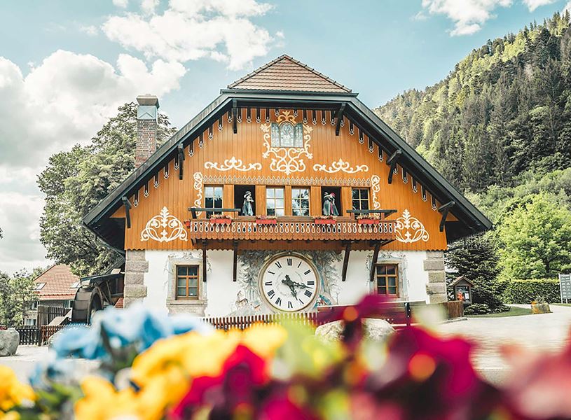 Hofgut Sternen building with clock, flowers and forested mountain backdrop