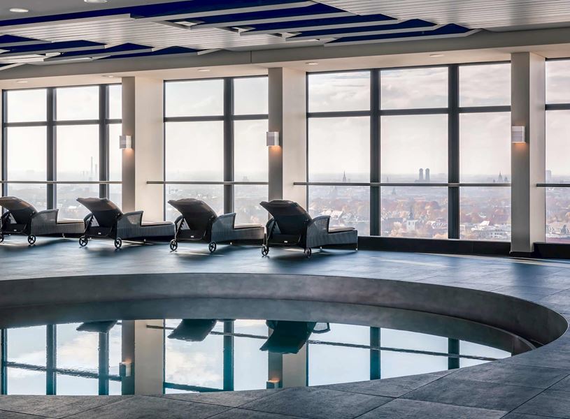 Indoor pool with city view and loungers at Arabella Sheraton Munich