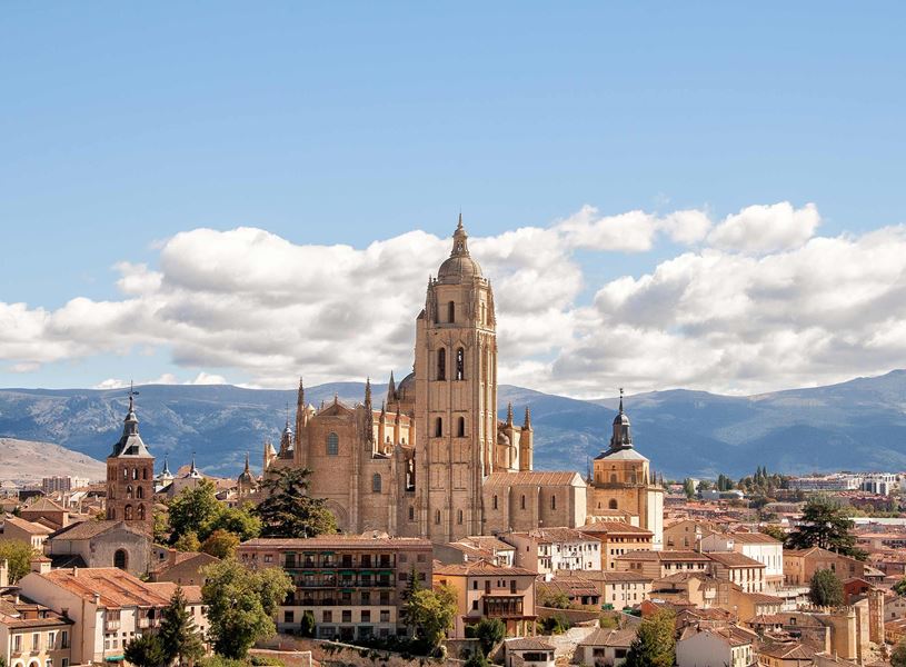 Segovia Cathedral towering over city rooftops with mountain backdrop