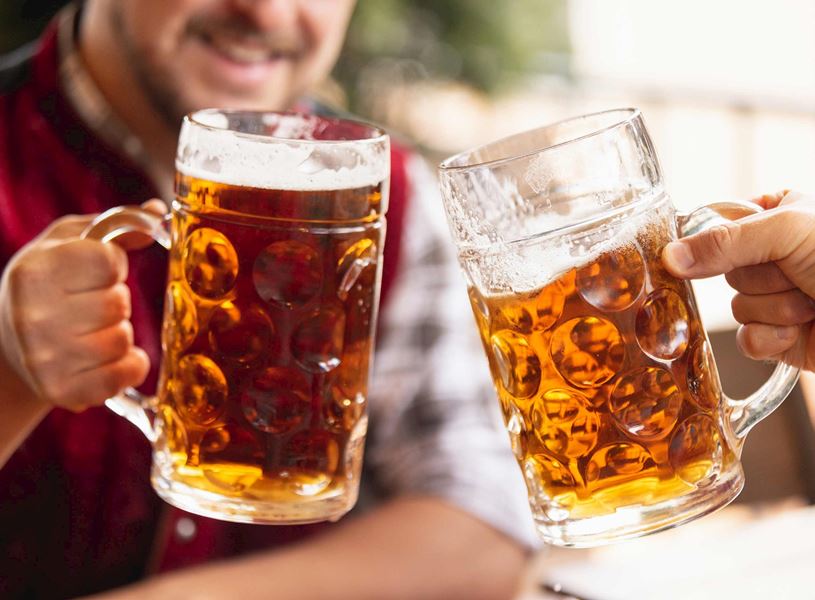 Close-up of two hands clinking glass beer mugs 