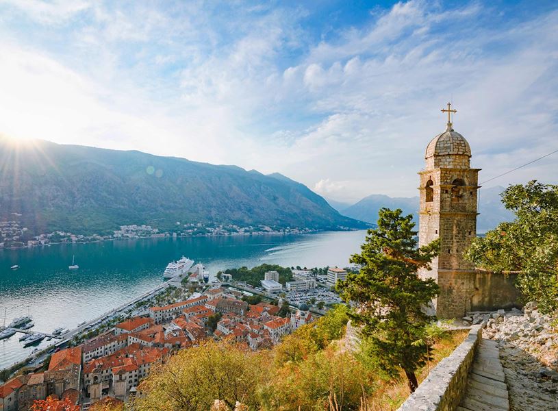 Panoramic view of Kotor Bay in Montenegro with church tower, red rooftops and cruise ship