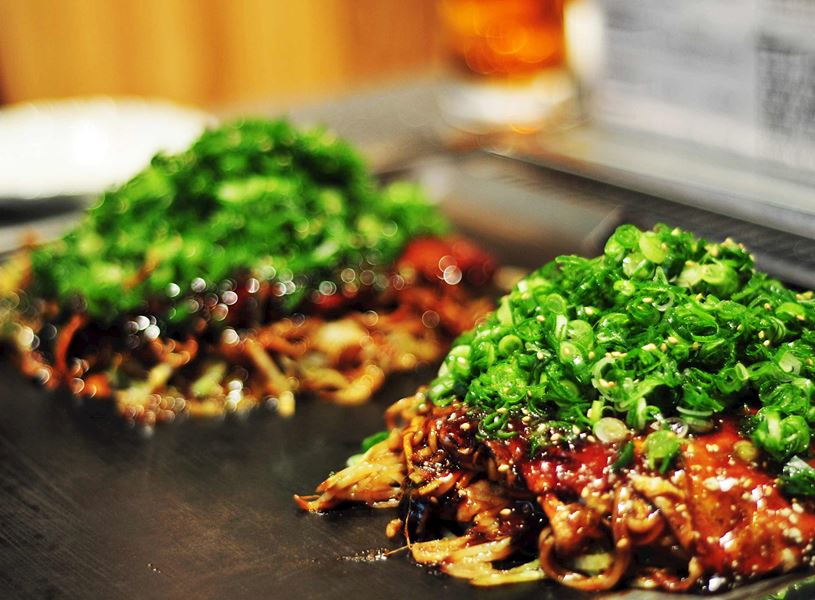 Two savoury okonomiyaki topped with fresh chopped green onions, Hiroshima, Japan