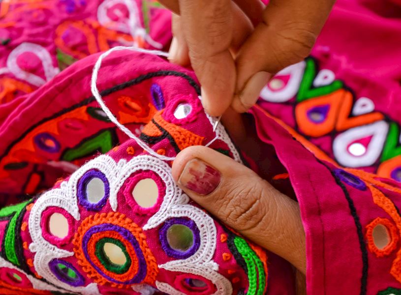 Close up of hands stitching vibrant fabric at Ranthambore studio, India