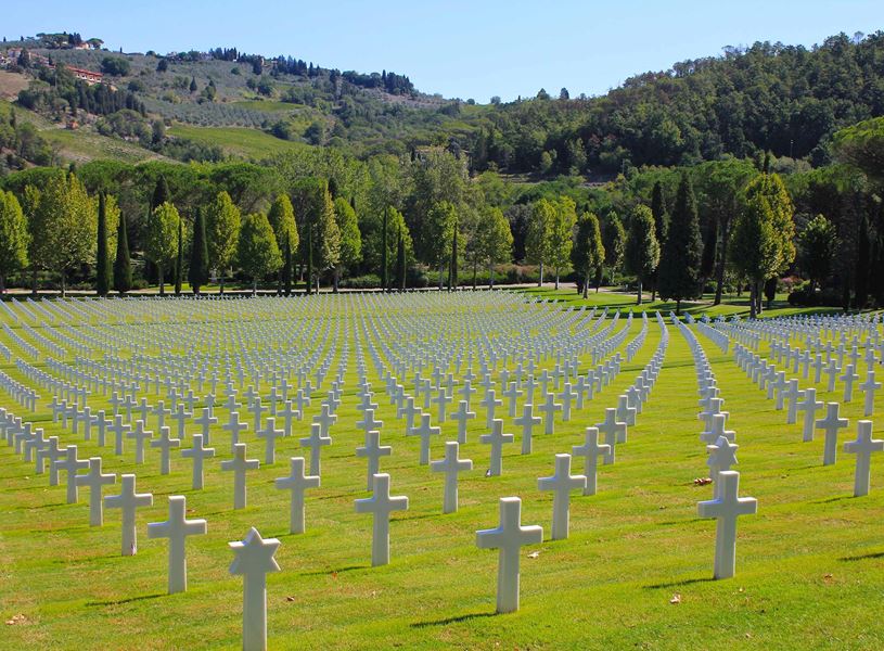 Rows of white crosses at Florence American Cemetery surrounded by green hills