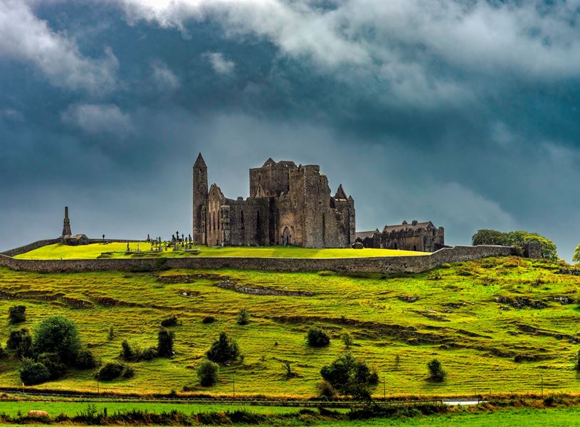 Rock of Cashel ruins on hilltop with dark cloudy sky