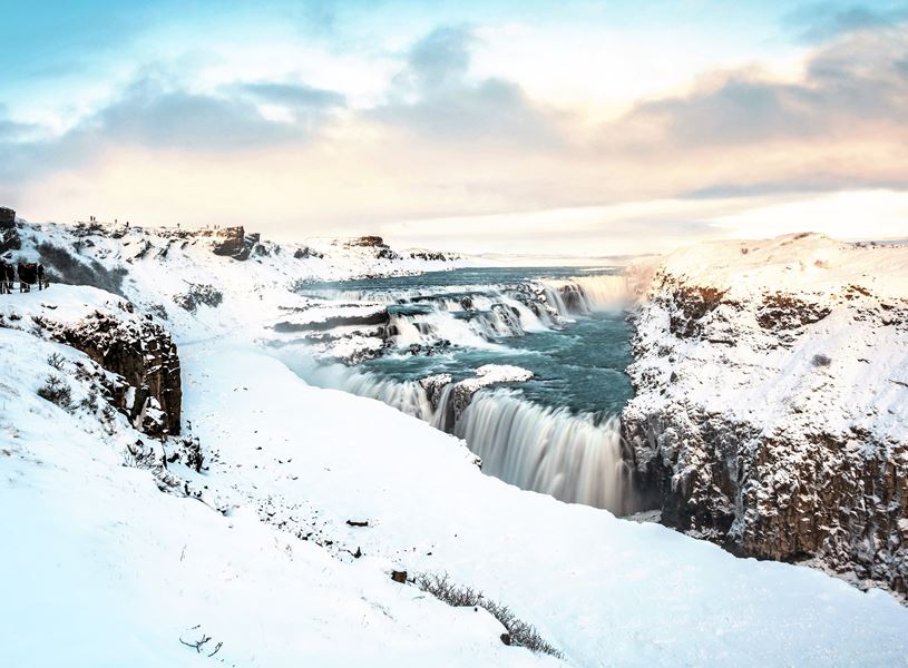 Snow-covered Gullfoss waterfall cascading through icy canyon landscape