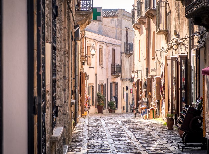 Narrow cobblestone street lined with stone buildings and balconies in Erice