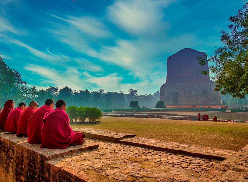 Buddhist monks sitting together near stupa in Sarnath, India