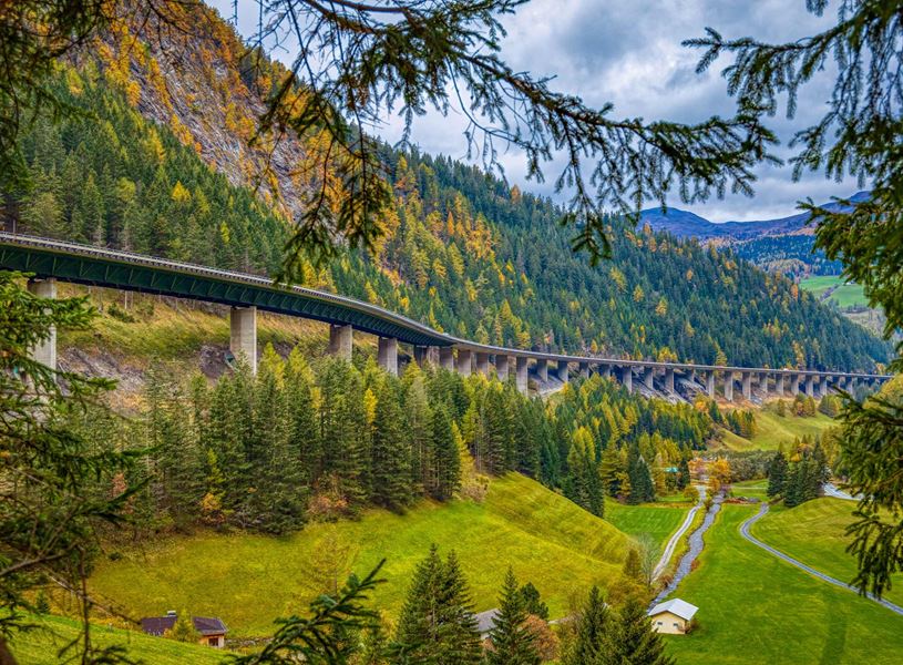 Brenner Pass viaduct winding through alpine valley with autumn foliage