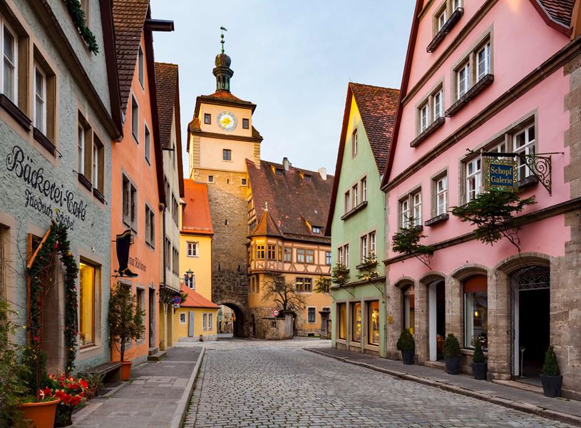 Cobblestone street with colourful buildings and clock tower in Rothenburg, Germany