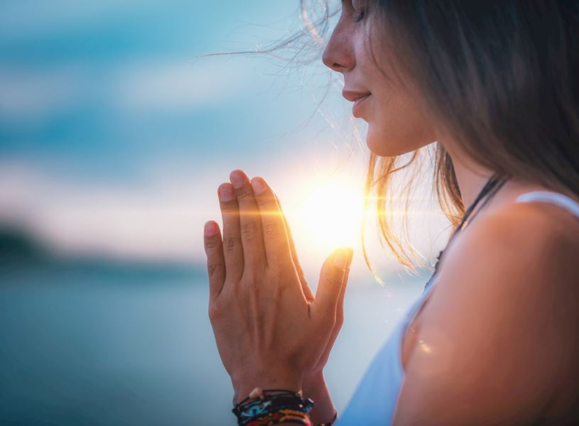 Person praying with hands folded during a private blessing ceremony