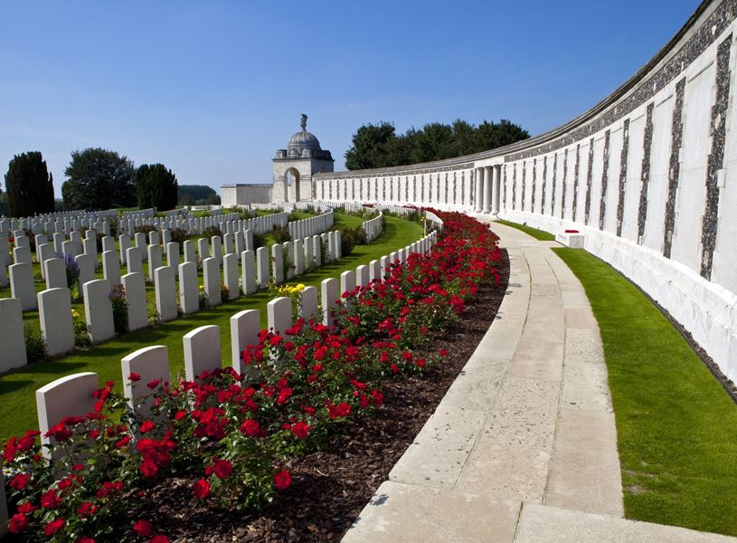 Tyne Cot Cemetery with white gravestones red flowers, memorial wall and domed monument