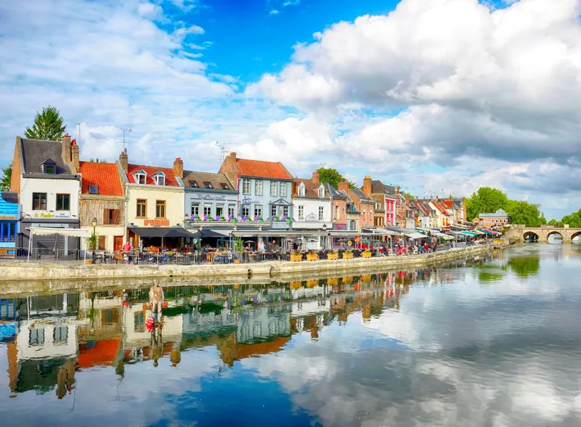 Colourful Amiens waterfront with cafés and arched stone bridge in France