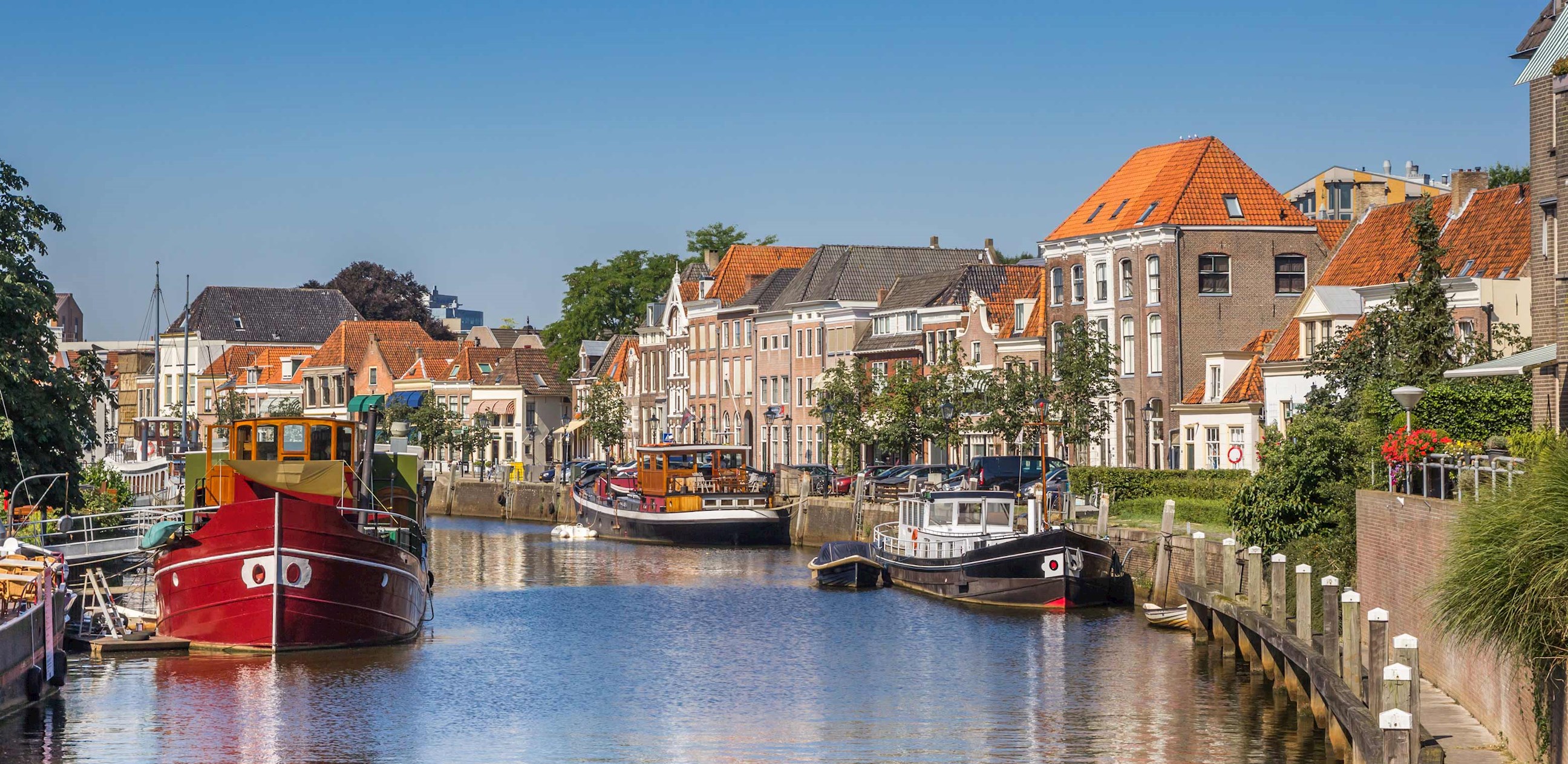 Colourful boats along canal with historic buildings in Zwolle, Netherlands