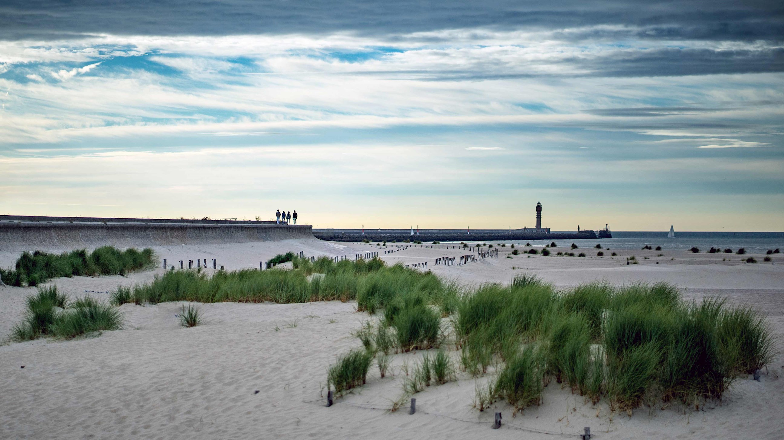 Dunkirk beach with grassy sand dunes, pier and lighthouse in France