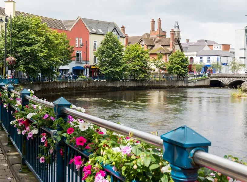 Riverside buildings and vibrant flowers along a scenic walkway in Sligo, Ireland