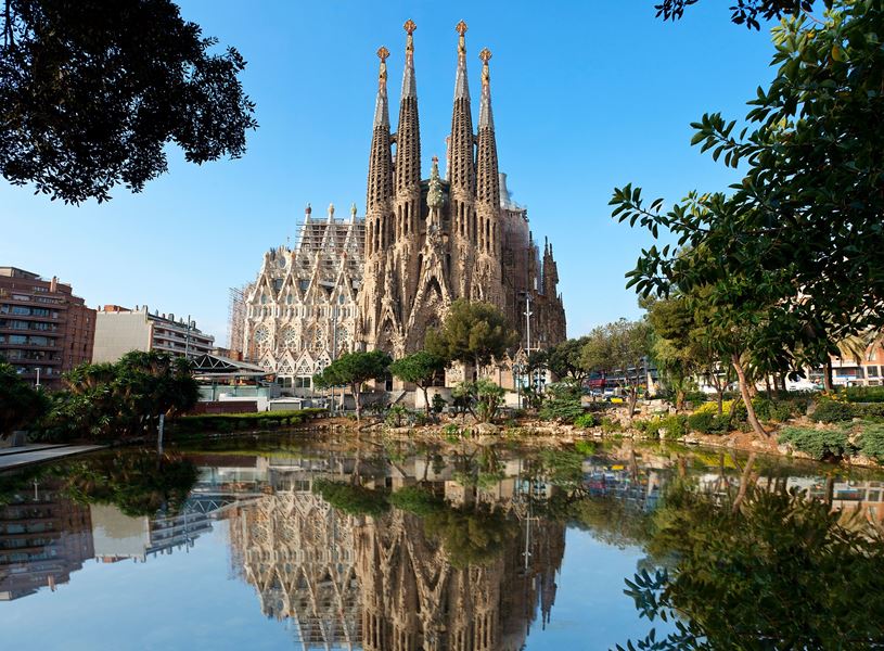 Sagrada Familia cathedral reflecting in water on a sunny day, Barcelona, Spain