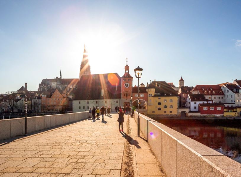 Stone Bridge in Regensburg with sun flare and cityscape view