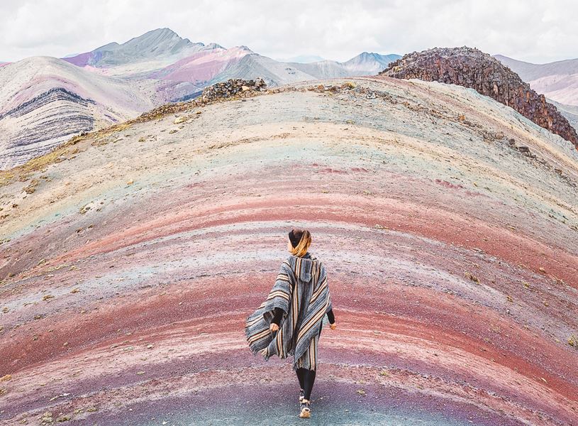 Traveller walking over the Rainbow Mountain during a hike in Cusco, Peru